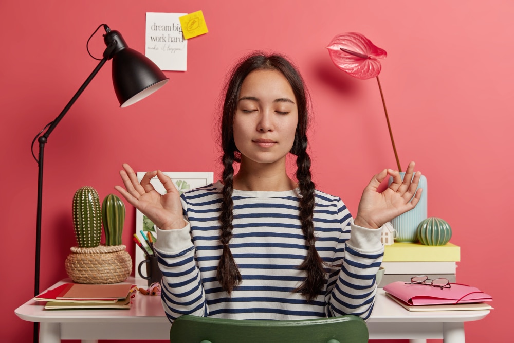 Woman practicing mindfulness at desk, representing stress reduction and improved employee engagement.
