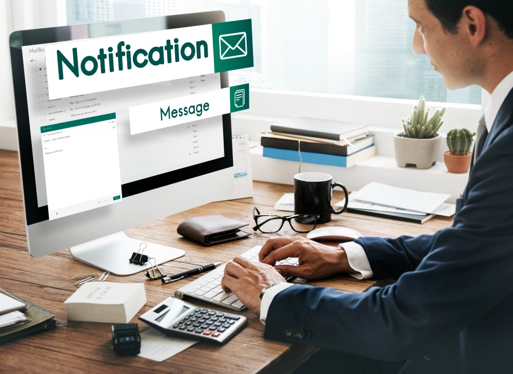 Person checking automated email notifications and reminders on a desktop.