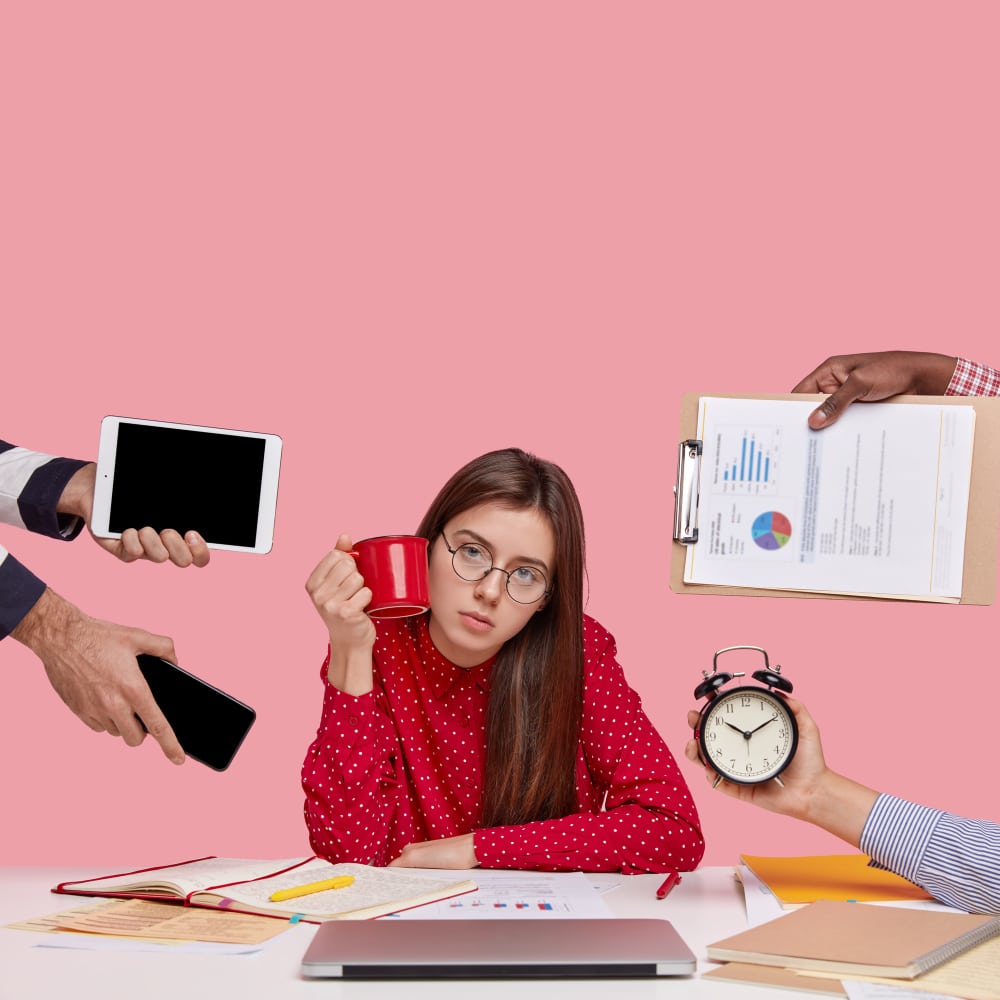 Stressed woman at desk surrounded by tasks, showing low engagement.