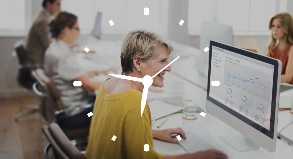 Employee working at a computer with a clock overlay, representing a time-consuming process in the workplace.
