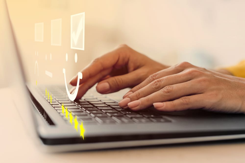 Person typing a performance review with rating icons on a laptop.