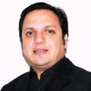 Man with dark hair wearing a black shirt, looking at the camera against a plain light background.